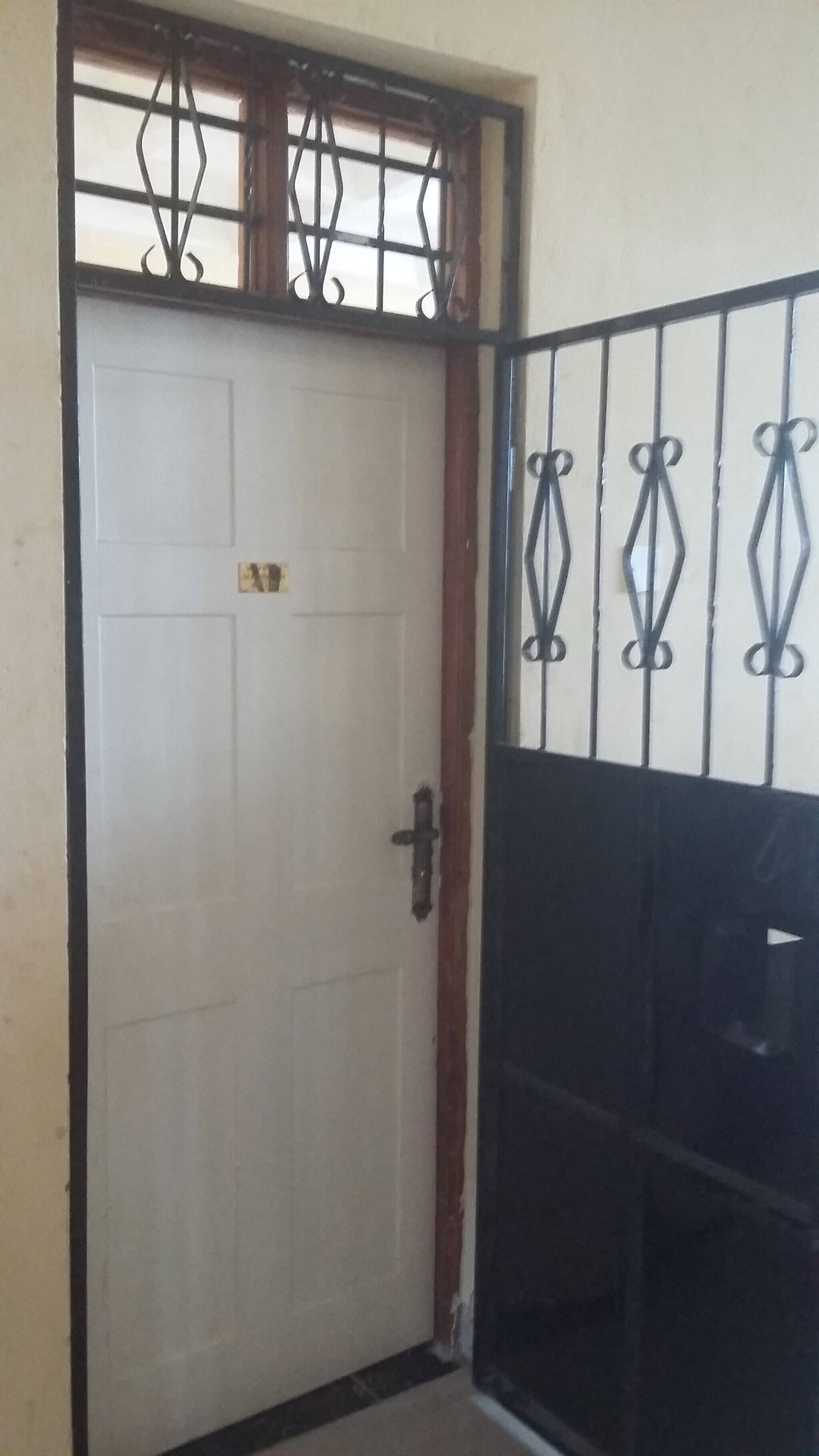 Uma porta branca com grade de metal e detalhes metálicos decorativos.