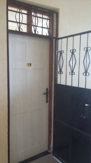 A white door with a metal gate and decorative metalwork. - Furnished Flat Apartment Bamburi Beach Mombasa (Mombasa)