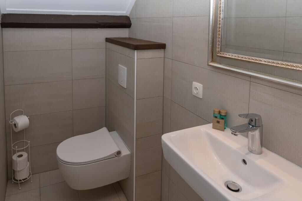 Een badkamer met toilet, wastafel en spiegel.