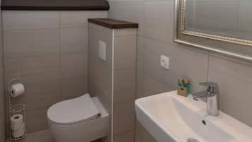 Een badkamer met toilet, wastafel en spiegel.