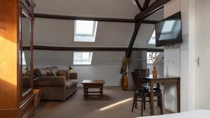 A room with a loft bed, a sofa, a dining table, and a TV mounted on the wall. - hcrslandswelvaren (Aardenburg)