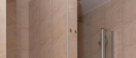 Un baño con ducha de vidrio, inodoro y lavamanos.