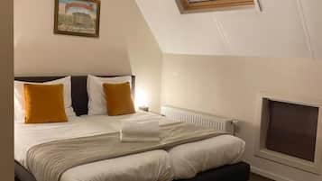 Un dormitorio con cama, radiador, ventana y un cuadro en la pared.
