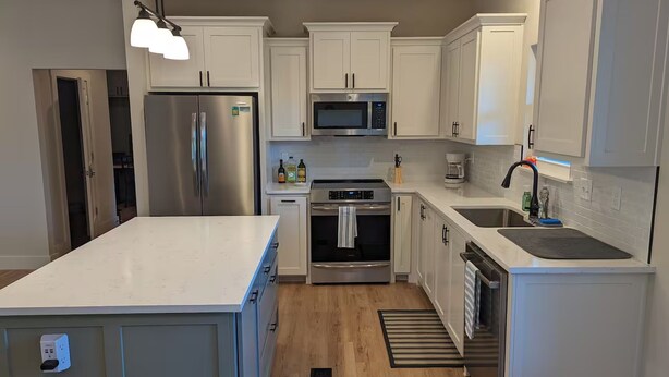 Una cocina moderna con armarios blancos, electrodomésticos de acero inoxidable y una isla grande.