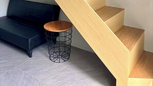A modern staircase with wooden steps and a black upholstered bench. - Olive Athena Guesthouse (Denpasar)