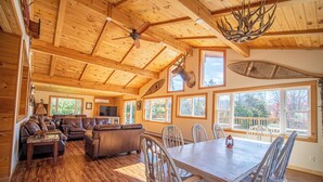 Eine geräumige Holzhütte mit rustikalem Interieur, einem großen Esstisch und einer gemütlichen Sitzecke.