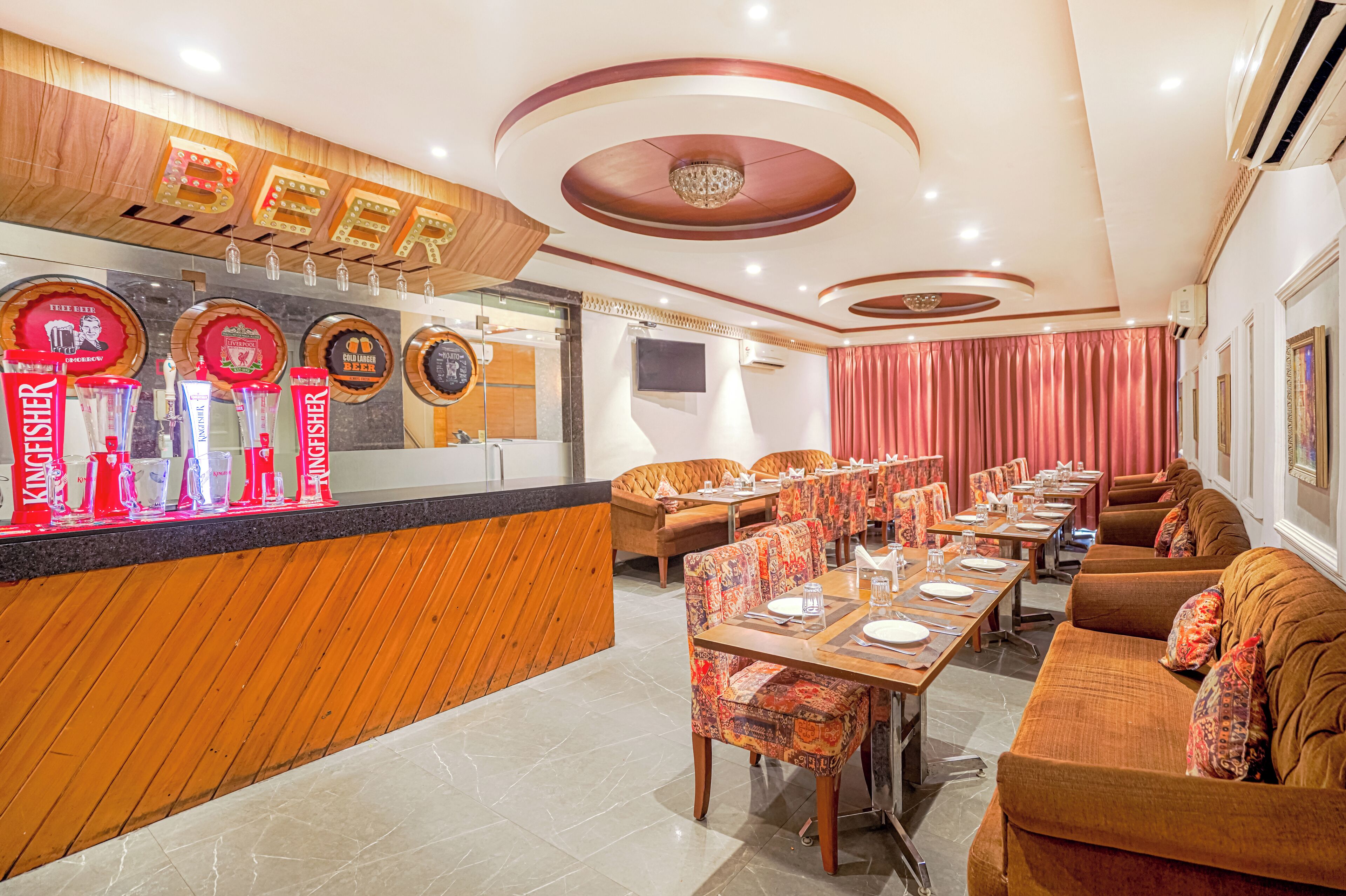 A restaurant with a wooden counter, multiple tables, and a variety of seating options including sofas and chairs.