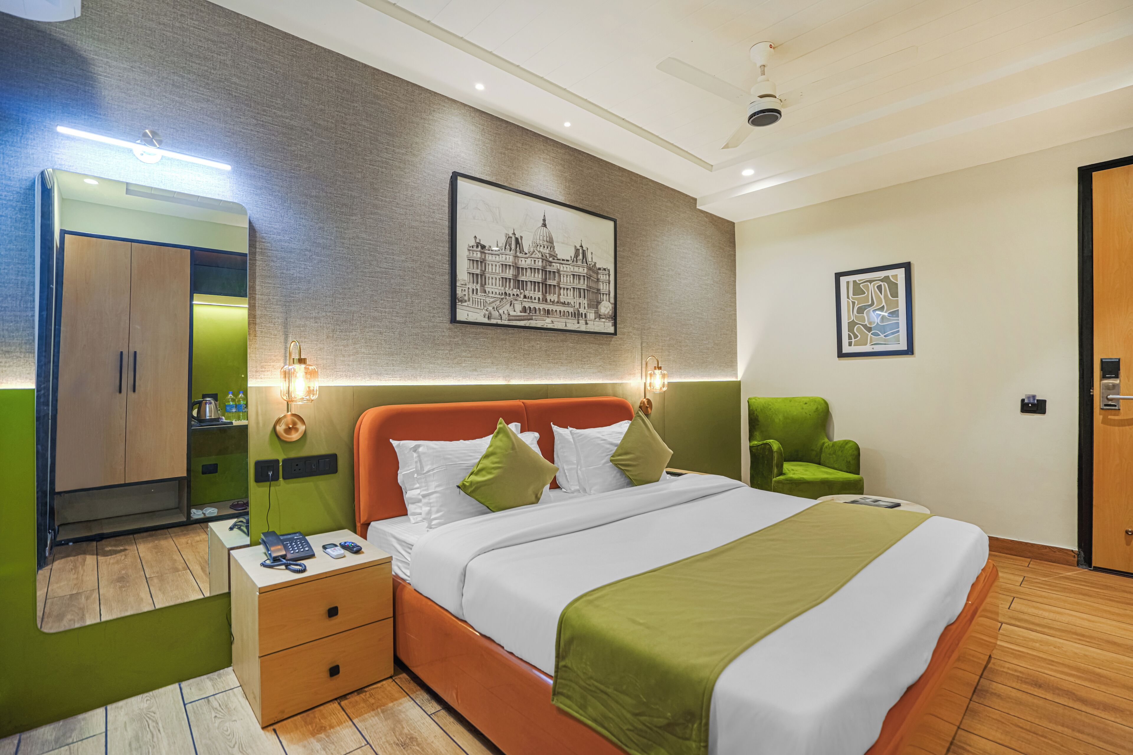 A hotel room with a bed, green armchair, and a wardrobe.