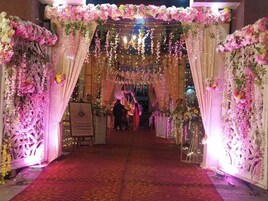 Una entrada ornamentada con decoraciones florales y luces de adorno, que conduce a una zona de recepción.