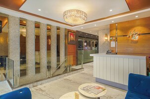 Un hall de hotel con una recepción, un área de descanso y una escalera que sube a otro piso.