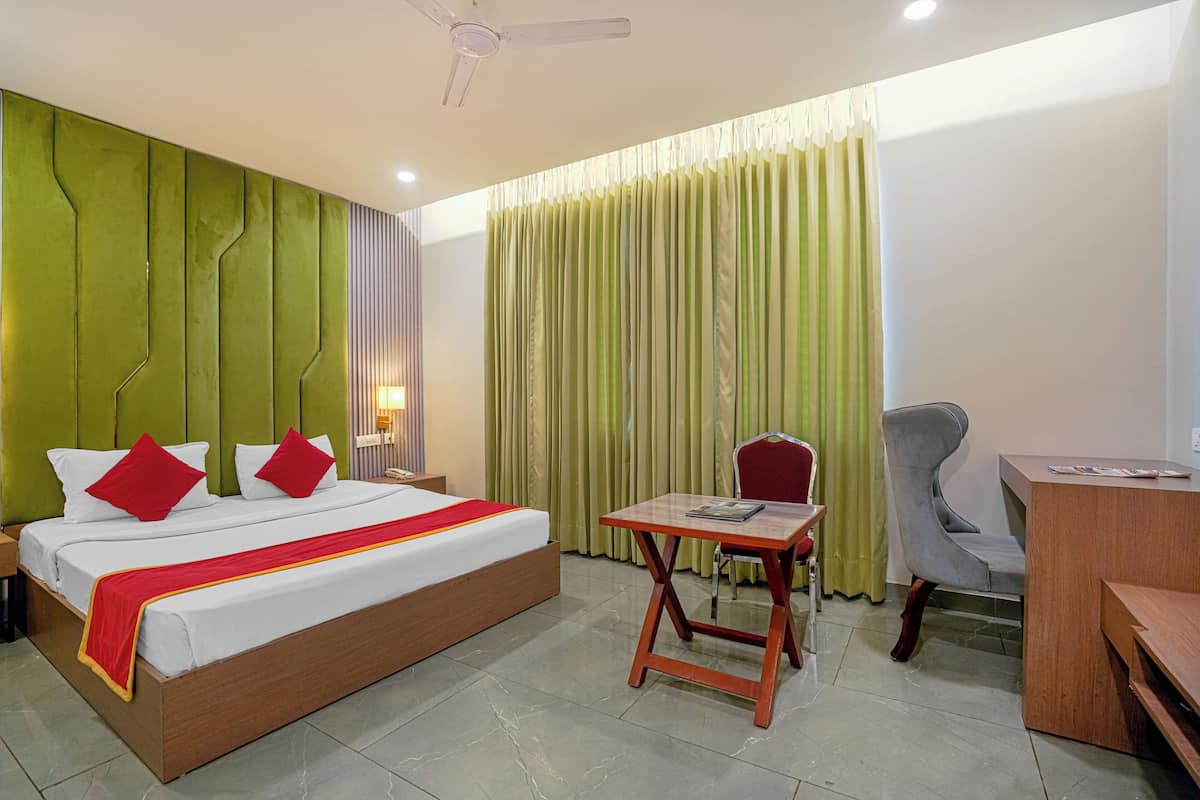 Une chambre d’hôtel avec un lit, un bureau, une chaise et des rideaux.