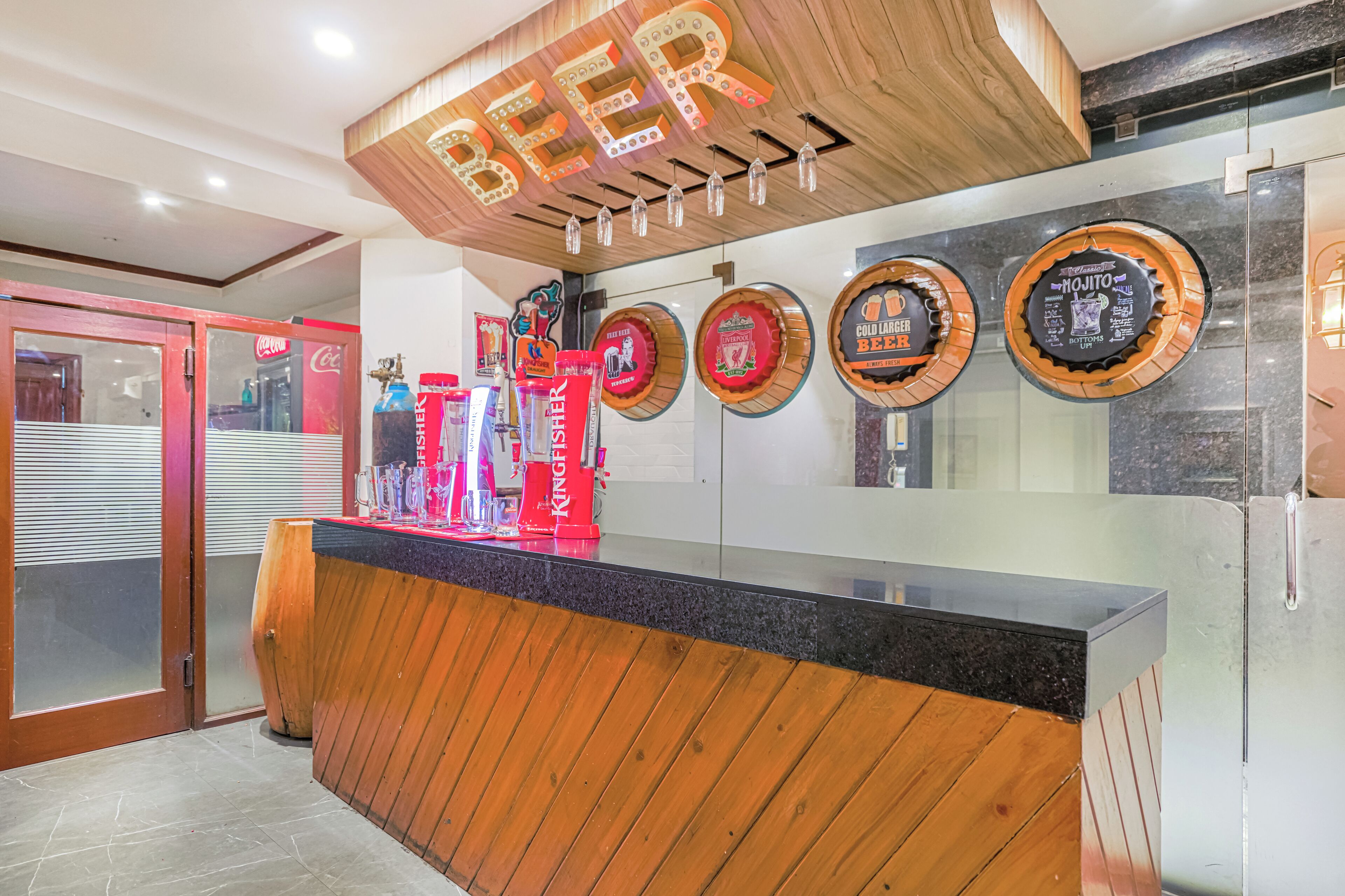 A bar area with a wooden counter, a neon sign reading "BEER", and beer taps labeled with various brands.