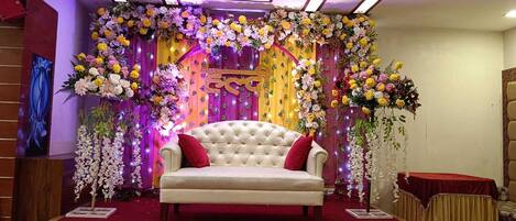 A stage with a white sofa, red cushions, and a red carpet.