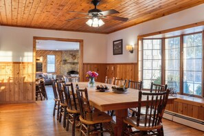 A wooden dining area with a large table, chairs, and a ceiling fan. - Mountainview Estate | Private Lake + Heated Pool, Spa + Game Room | 12BR Retreat (Hensonville)