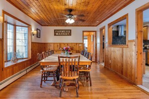 A dining area with a wooden table and chairs, a ceiling fan, and a sign reading 'Farmers Market.' - Mountainview Estate | Private Lake + Heated Pool, Spa + Game Room | 12BR Retreat (Hensonville)