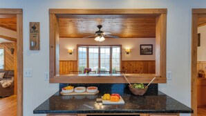 Une cuisine avec des meubles de rangement en bois, un plan de travail noir et un ventilateur de plafond.