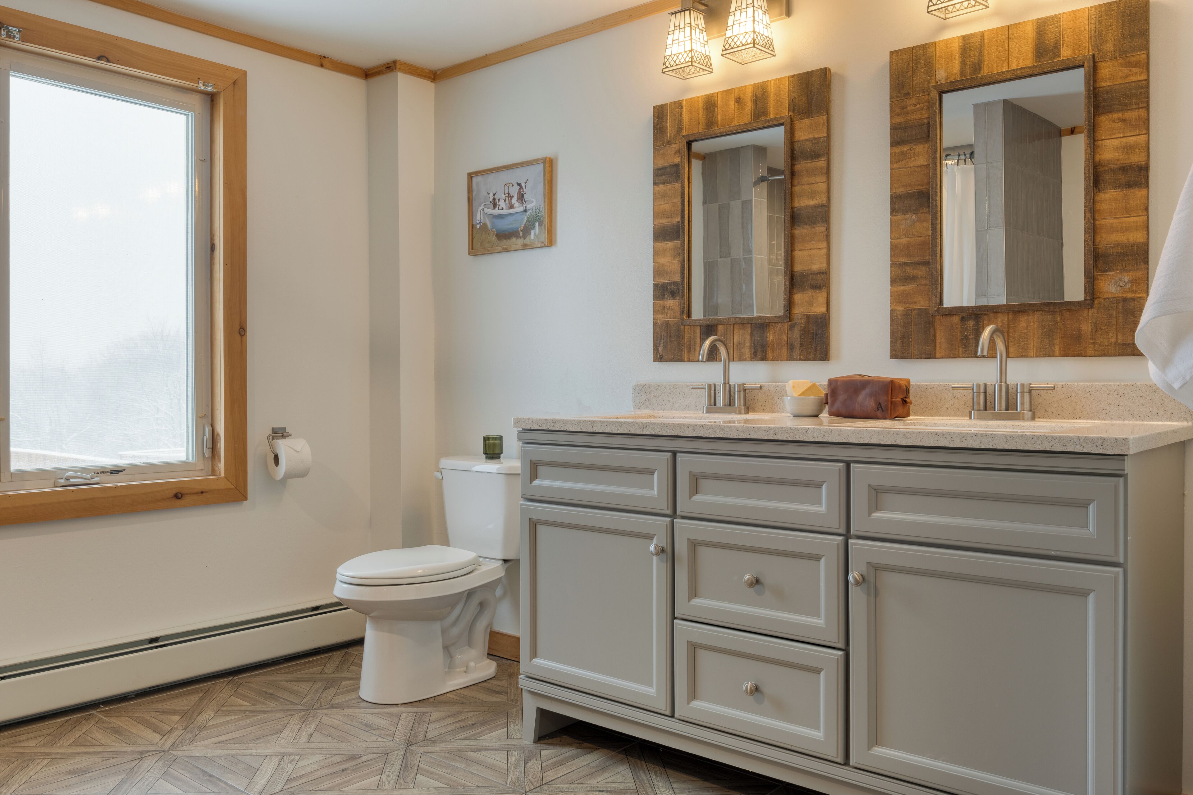 Un baño con tocador de madera, inodoro, ventana y espejo.