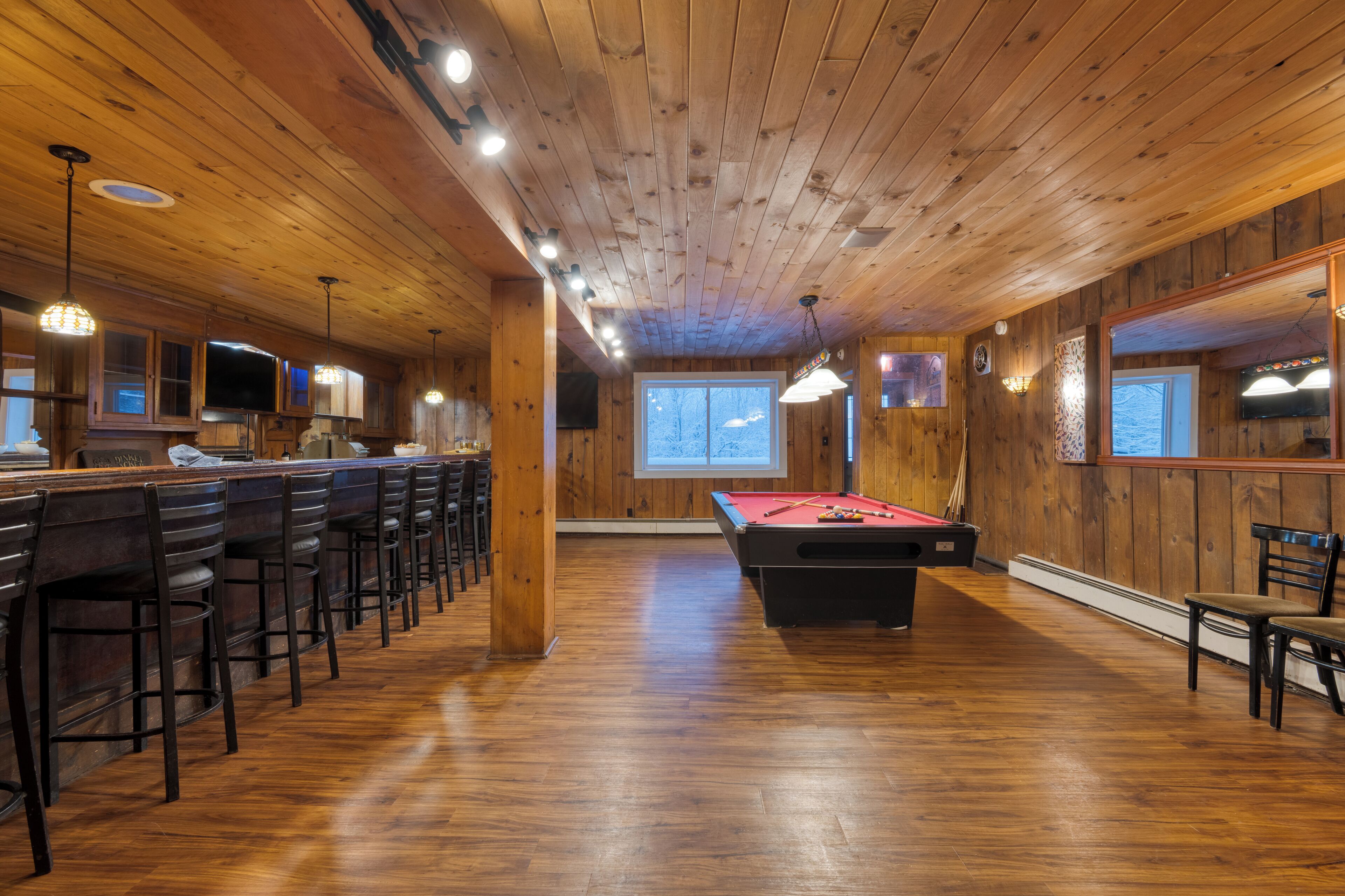 Un intérieur en bois comprenant une table de billard, un coin bar et des sièges.