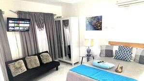 Ein Hotelzimmer mit einem Bett, einem Sofa, einem Fernseher und einem Bild an der Wand.