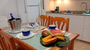 Een eettafel gedekt met borden, bekers, een fruitschaal en een metalen bak.
