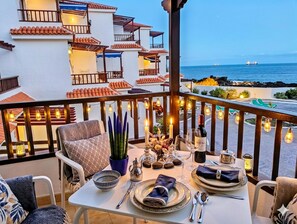 A dining area with a table set for two, overlooking a coastal view with buildings and a ship in the distance. - Charming 1-Bedroom Apartment with Sea Views in Breña Baja (Breña Baja)