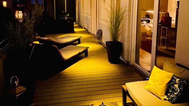 An outdoor deck with wooden flooring, a sofa, a coffee table, and a potted plant. - Penthouse with XL terrace | including parking space | top connection to the old town (Nürnberg)