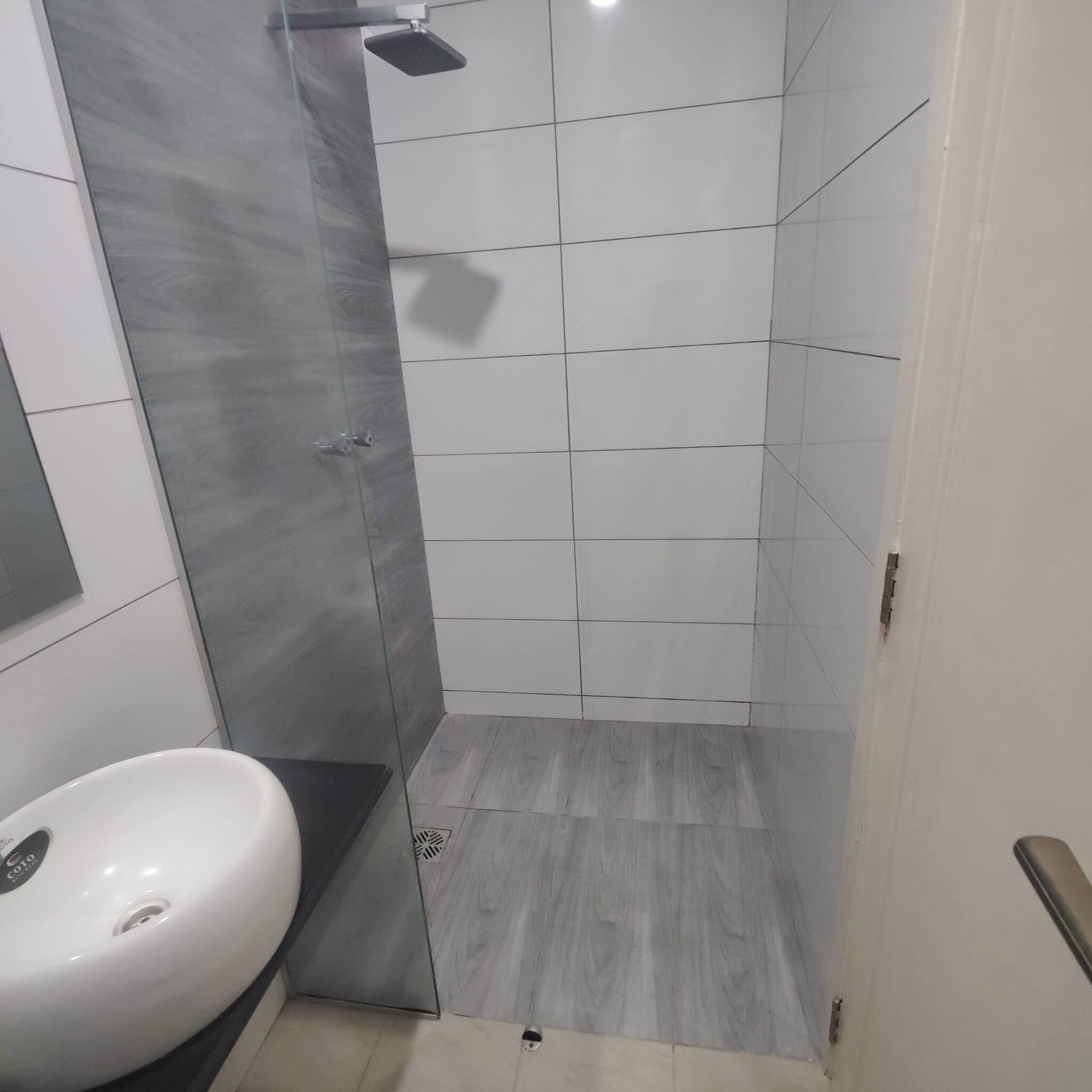 A bathroom with a shower, a sink, and tiled walls.