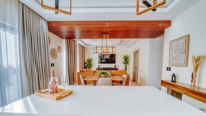 Cozinha moderna com ilha central, teto de madeira e área de jantar com televisão.
