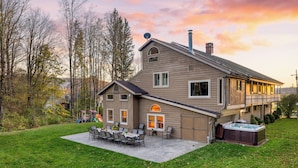 Ein zweistöckiges Haus mit Terrasse, Whirlpool und einer Veranda.