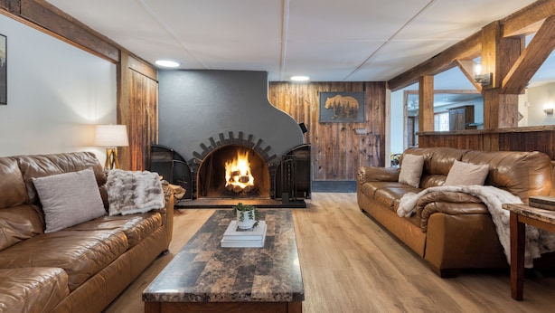 Ein gemütliches Wohnzimmer mit Kamin, Ledersofas und Holzböden.