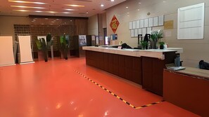 A reception area with a red floor, a reception desk, and a wall with framed certificates. - Beijing CBD - Cozy suite with Queen bed  (Beijing)