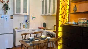 Une cuisine compacte avec des meubles blancs, un four encastré et un coin repas avec une table dressée pour deux personnes.