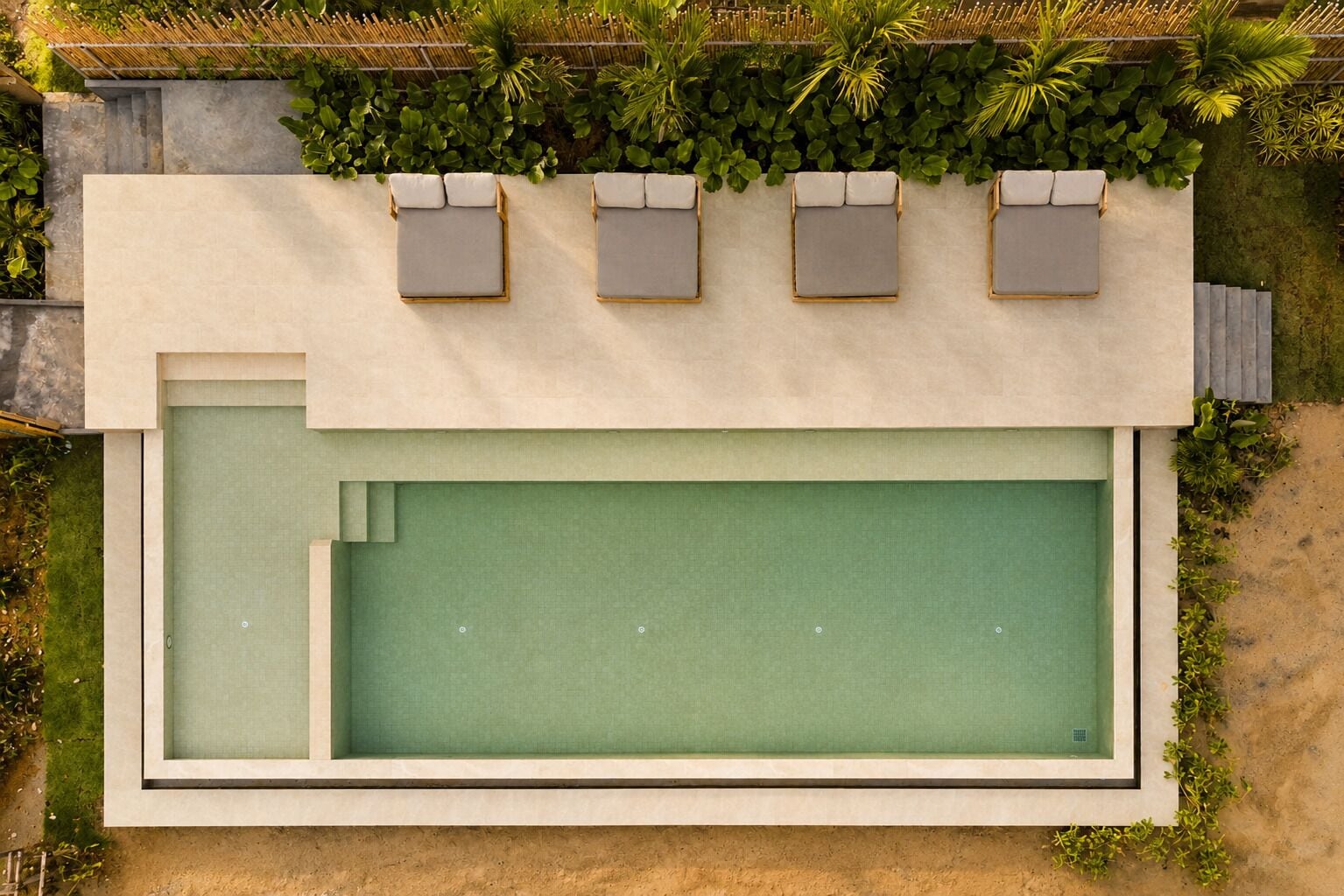 An aerial view of a swimming pool with a built-in seating area and a surrounding garden.