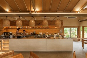 A modern bar with wooden accents, hanging lights, and a barista preparing drinks. - Amber Yao Noi (Ko Yao)