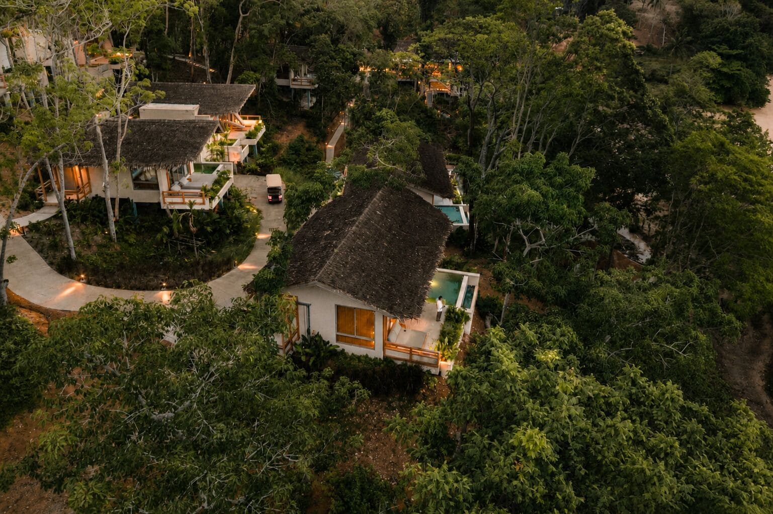 Ein Resort mit strohgedeckten Villen, umgeben von dichtem Grün.