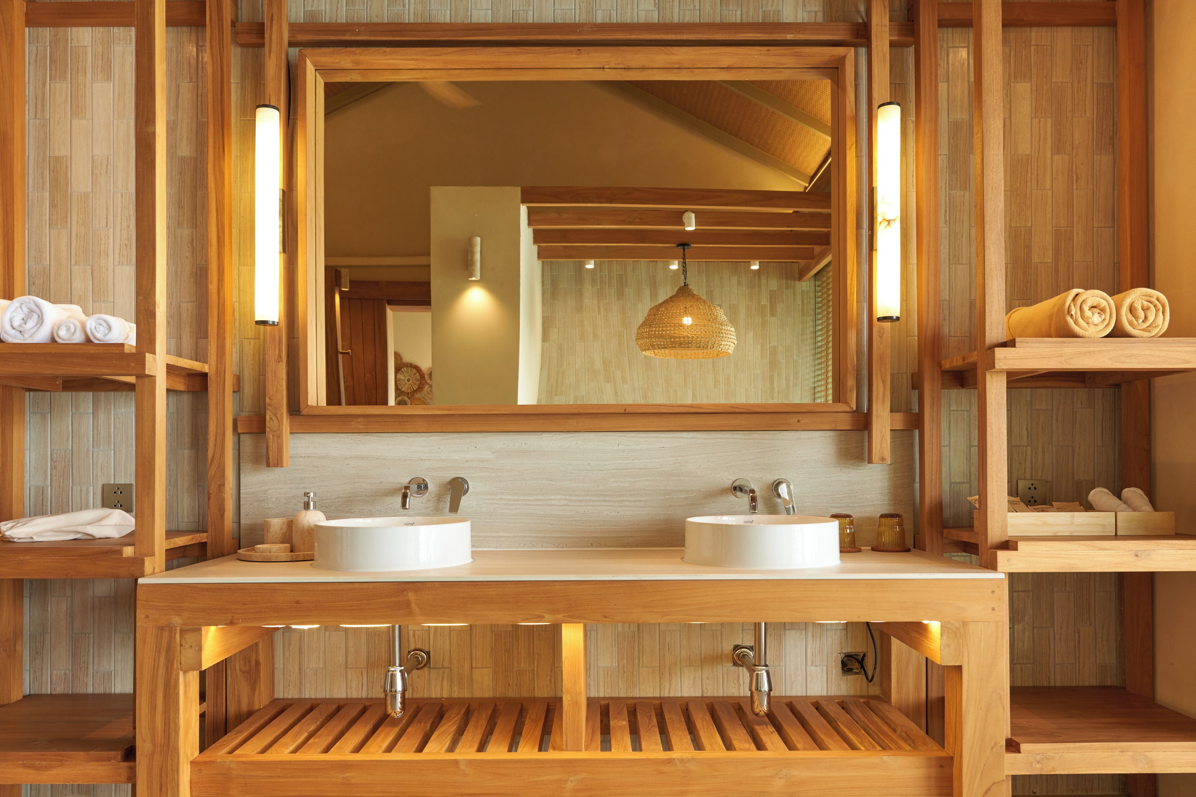 A wooden bathroom with two sinks, a large mirror, and a hanging light fixture.
