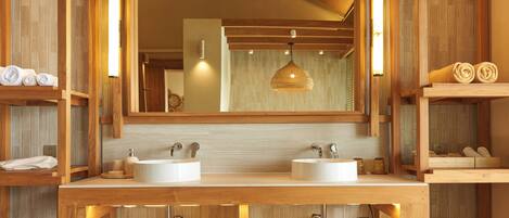 A wooden bathroom with two sinks, a large mirror, and a hanging light fixture.