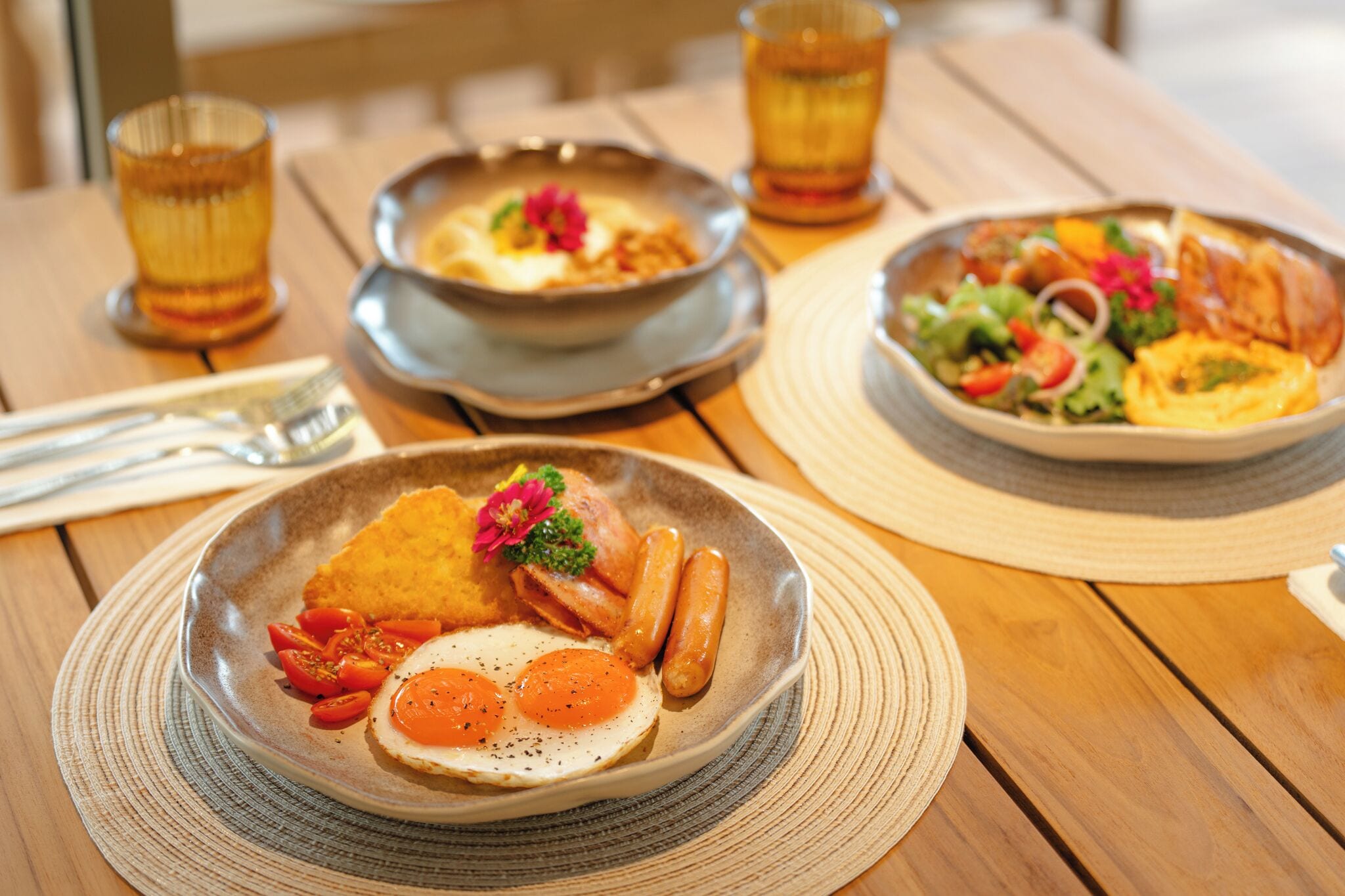 A wooden table with a plate of breakfast food including eggs, sausages, and tomatoes.