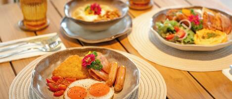 A wooden table with a plate of breakfast food including eggs, sausages, and tomatoes.