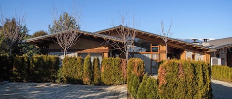 A modern house with a stone facade, wooden beams, and a paved driveway.
