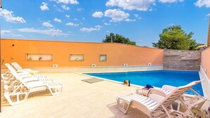 Ein Pool mit Liegestühlen und einer Steinmauer.