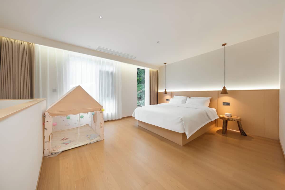 Ein Schlafzimmer mit Bett, Nachttisch, Vorhängen und einem Fenster.
