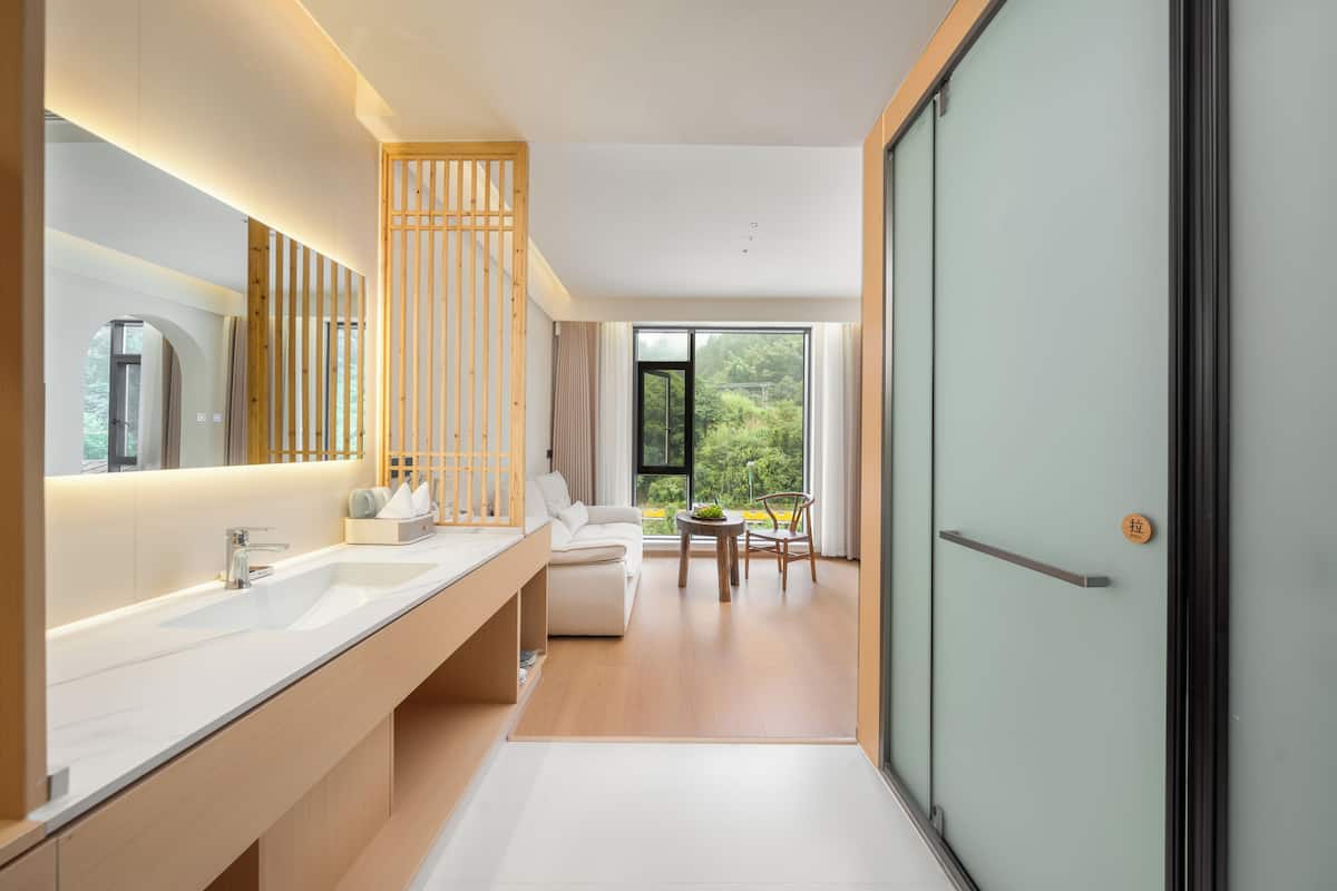 Ein modernes Badezimmer mit einem großen Spiegel, einem weißen Waschbecken und einer Holzwand.