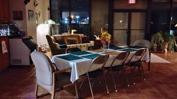 Comedor con mesa dispuesta para seis, sillas, un jarrón con flores y un sofá.