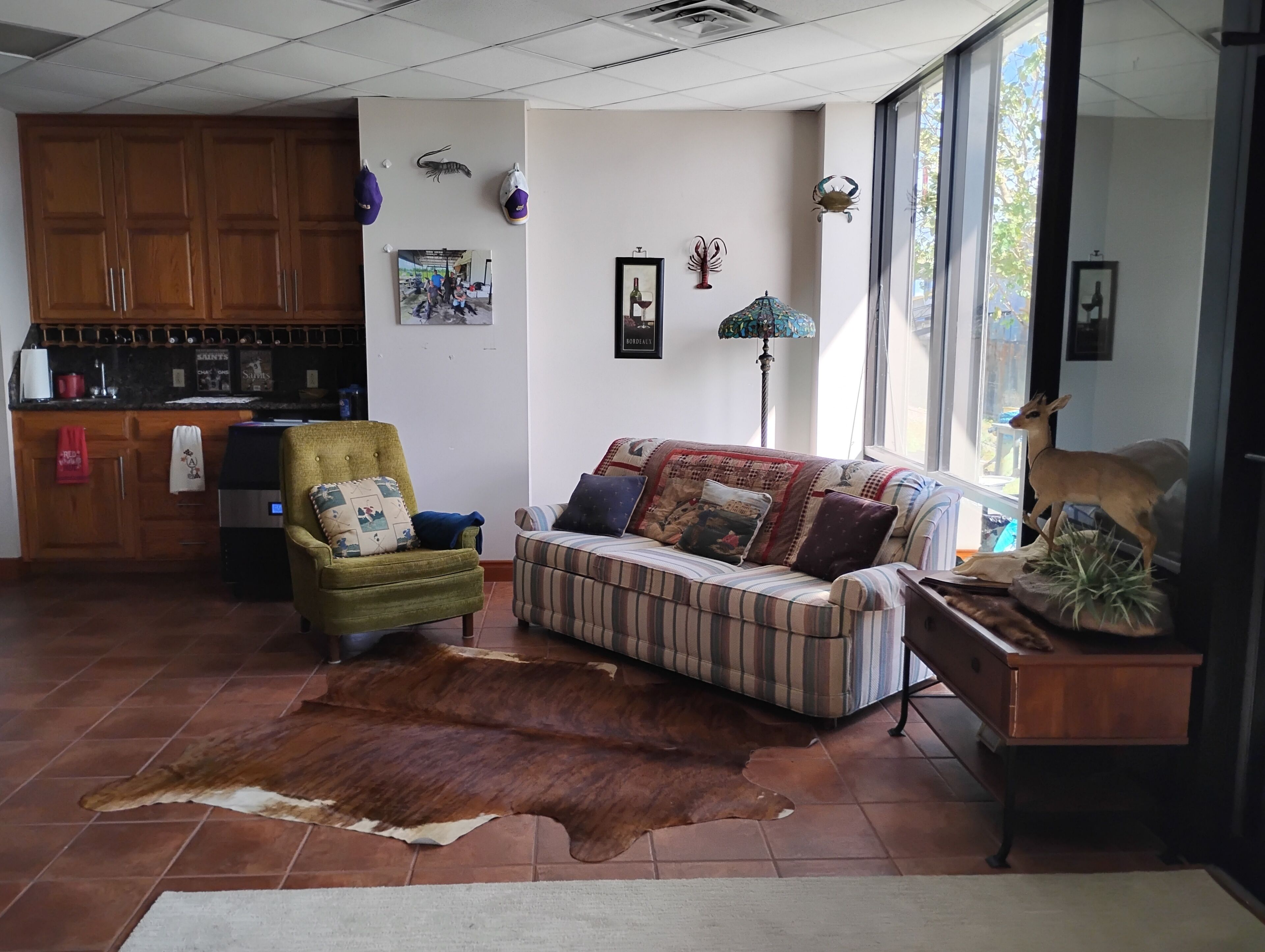 A living room with a sofa, armchair, rug, and a deer statue.
