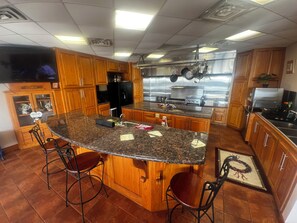 A kitchen with wooden cabinets, a granite countertop, a stainless steel refrigerator, and a built-in oven. - Waterfront 210’ dock boat launch 5 beds 2 bath. Great blue crab and fishing (Larose)