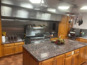 A kitchen with granite countertops, stainless steel appliances, wooden cabinets, and a large island. - Waterfront 210’ dock boat launch 5 beds 2 bath. Great blue crab and fishing (Larose)