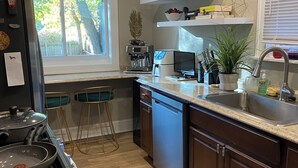 A modern kitchen with a stove, sink, and bar stools. - Stylish and comfortable! House close to downtown Akron. (Akron)