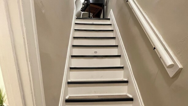 A staircase with white walls and wooden steps. - Stylish and comfortable! House close to downtown Akron. (Akron)
