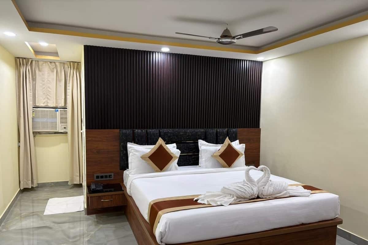 A hotel room with a large bed, wooden headboard, and a ceiling fan.